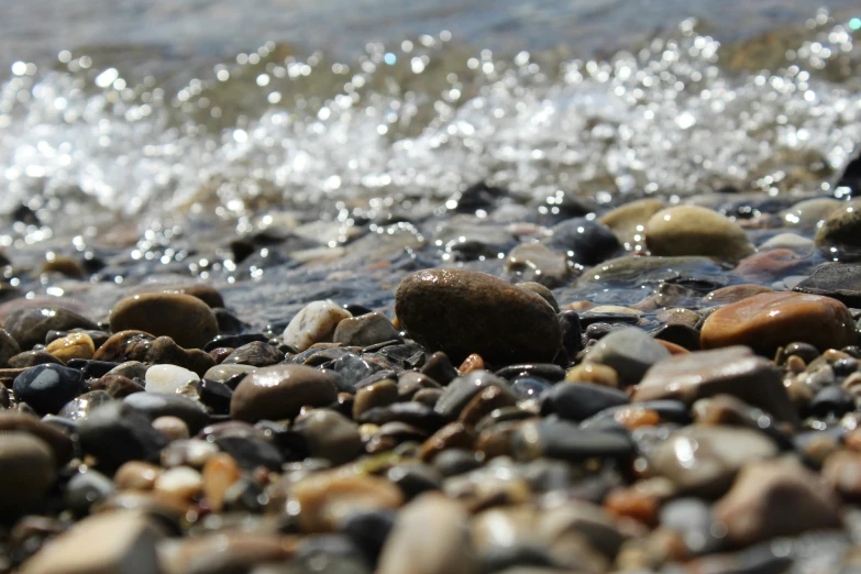 rocks on a beach with water splashing off the top