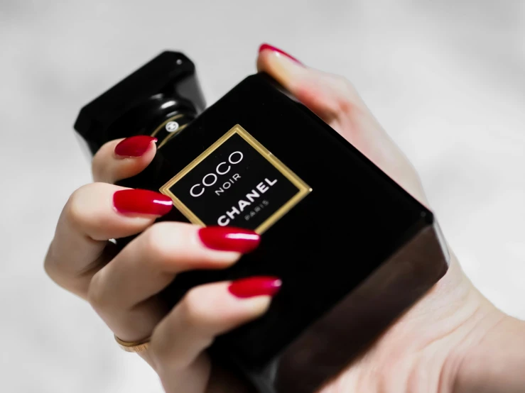 a woman is holding onto a black box and red nail polish