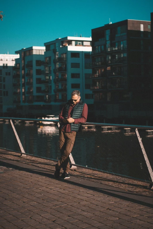 a man standing in front of a body of water with a building in the background