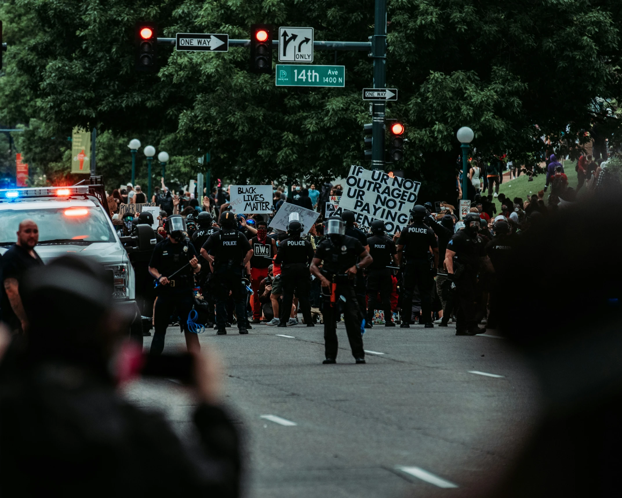 a police car driving on the road surrounded by protesters