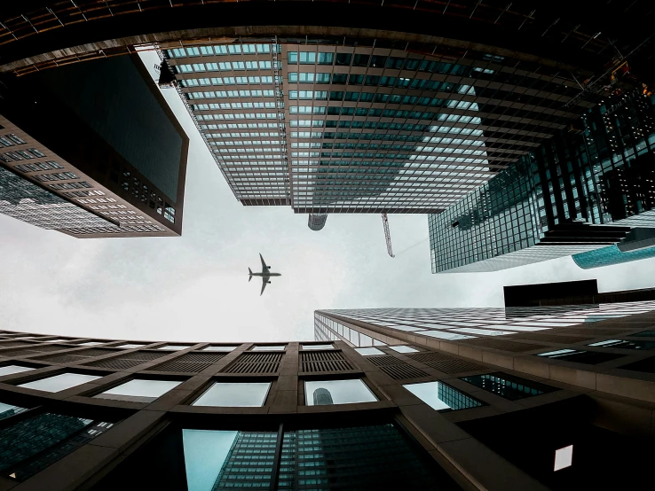looking up at an airplane flying high above the city skyline