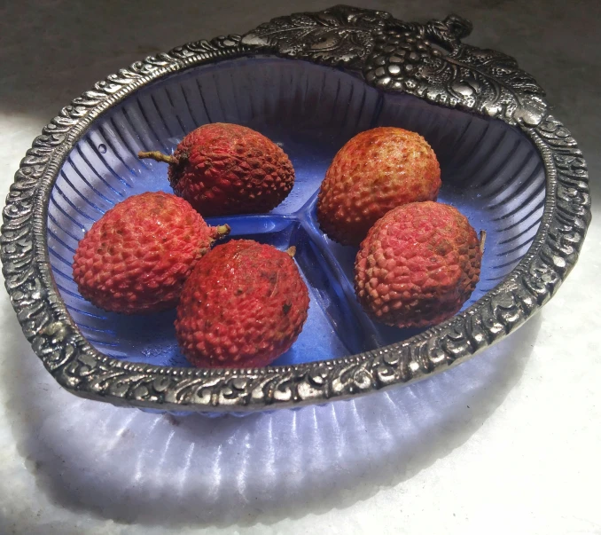there are four small red strawberries in this decorative bowl