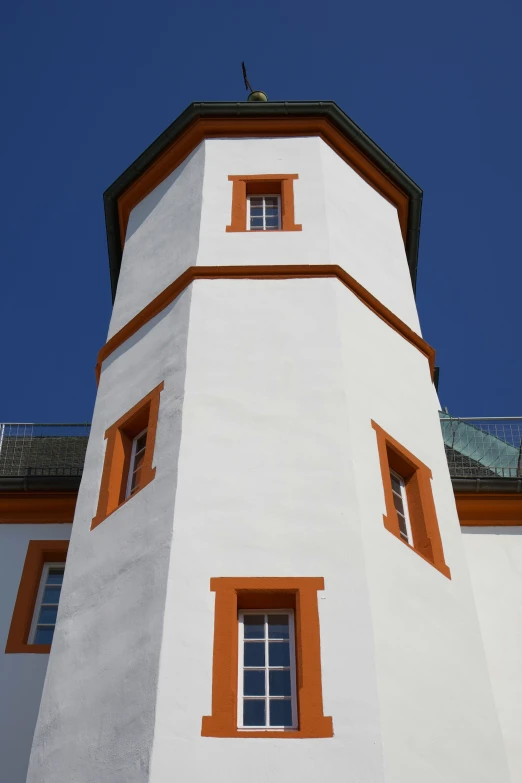 a white tower with two orange windows on it