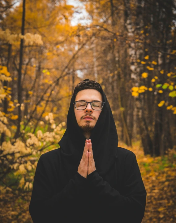 a man with glasses in the woods in front of trees