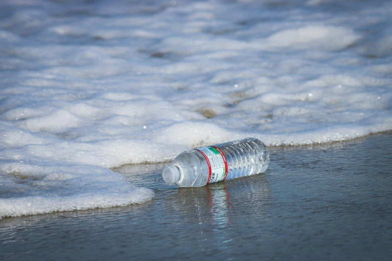 a bottle is sitting on a beach in the water