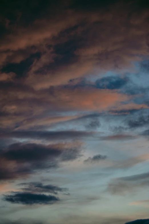 a airplane flying under a pink and purple cloudy sky