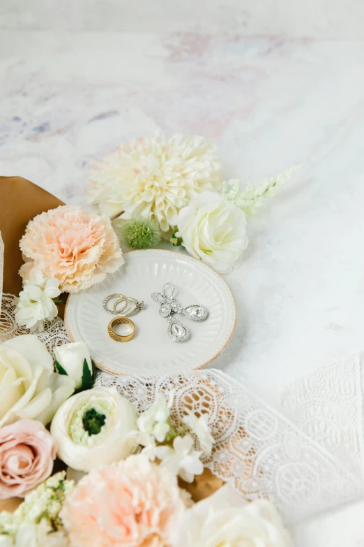 several rings sitting on top of a plate surrounded by flowers