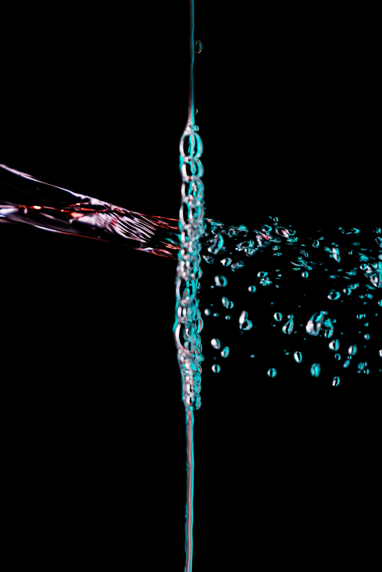 water is pouring into a glass with a black background