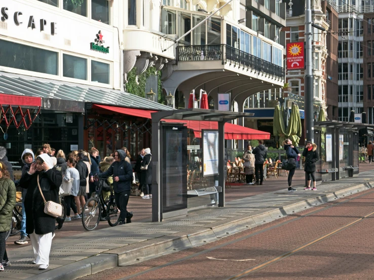 a crowd of people walking down a sidewalk next to a street