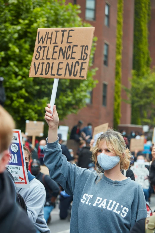 a woman wearing a face mask holding a sign