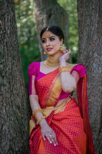 a woman in an orange sari and pink blouse posing