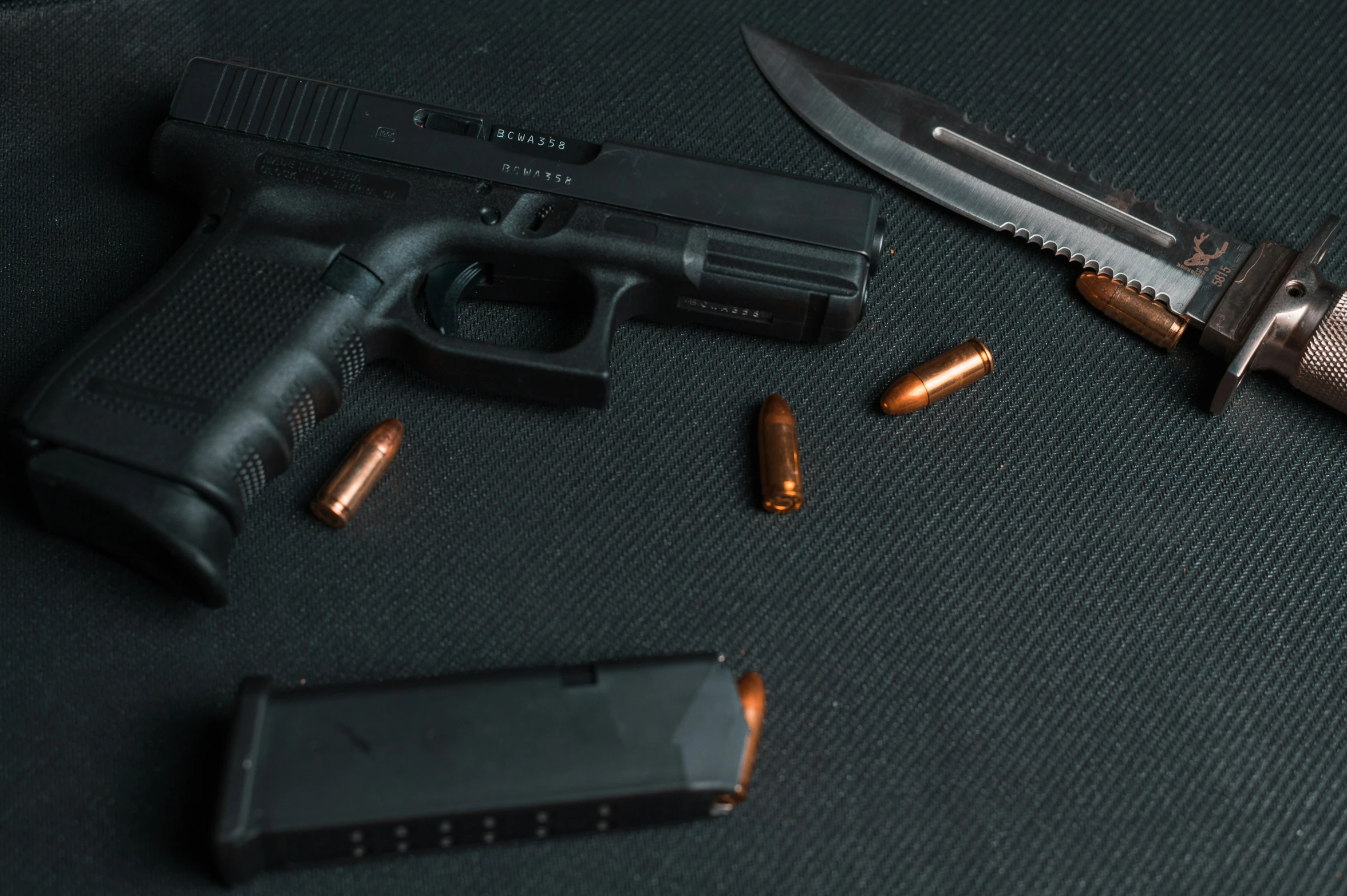 a black gun on a grey mat and two bullet casings