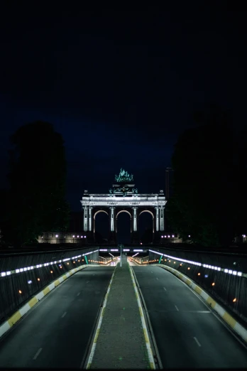 the entrance to a monument at night with traffic going down it
