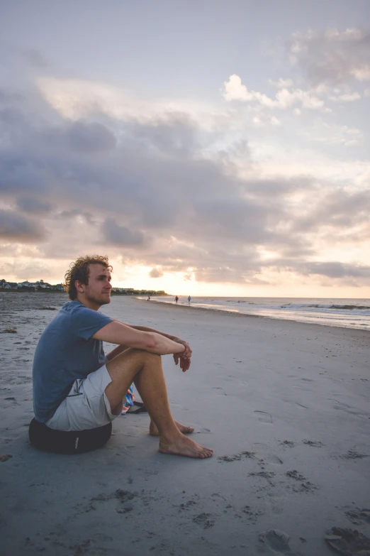 a man sitting on the beach looking at the sky