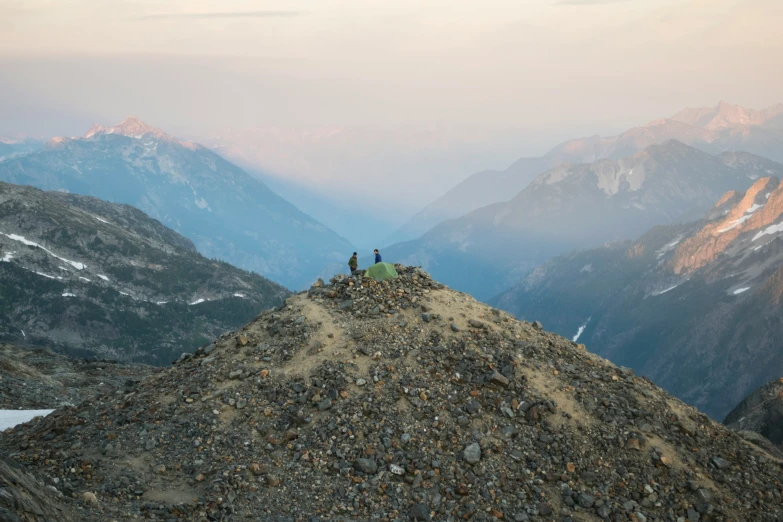 a rocky outcropping near mountains with two people sitting on top