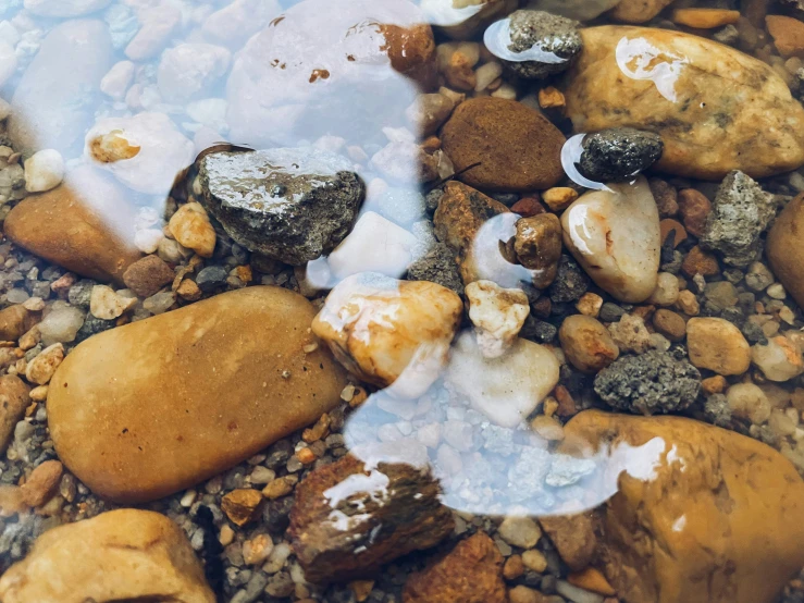 some rocks on the sand and water with white liquid