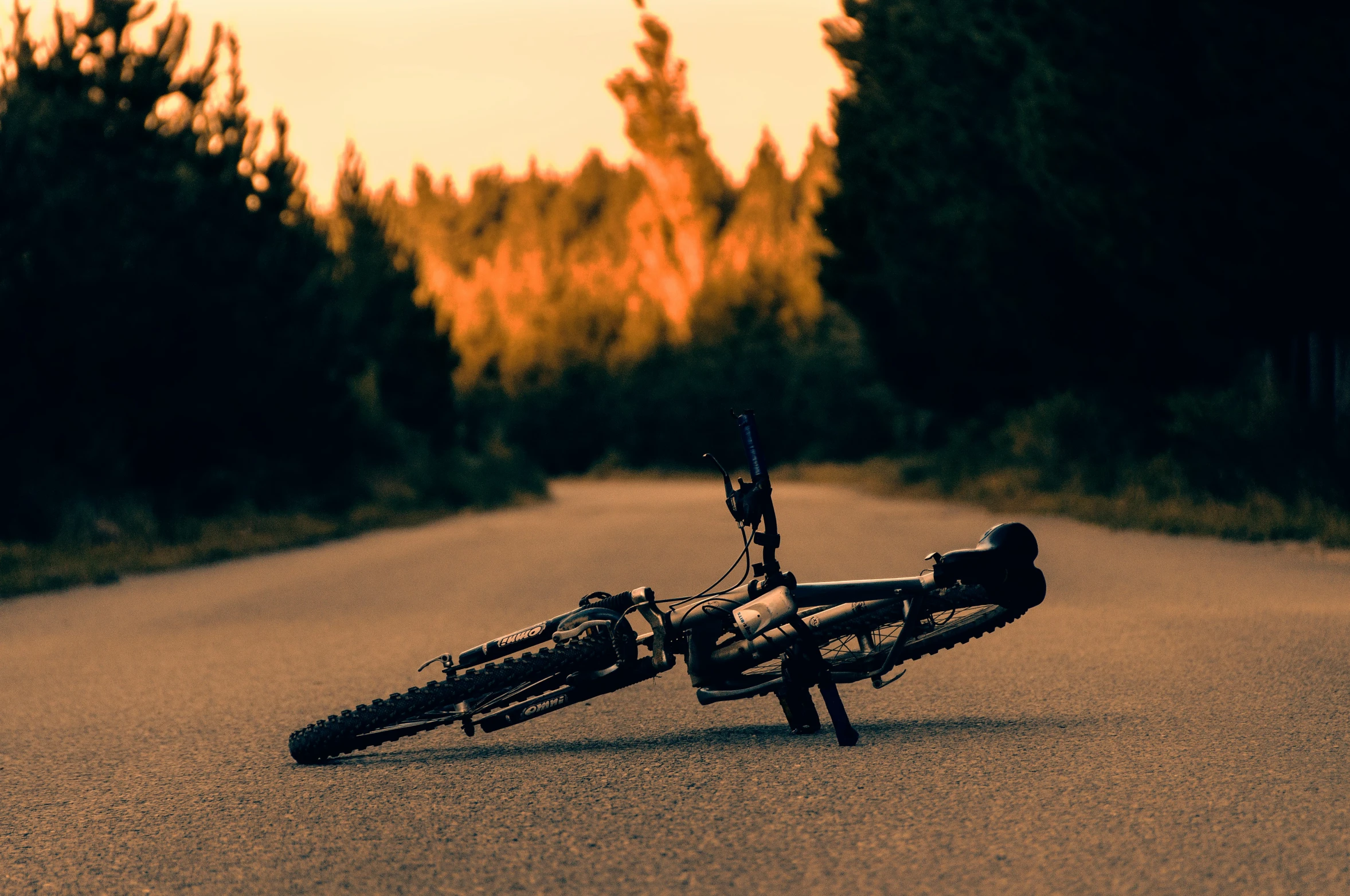 a bicycle lies upside down on the side of the road