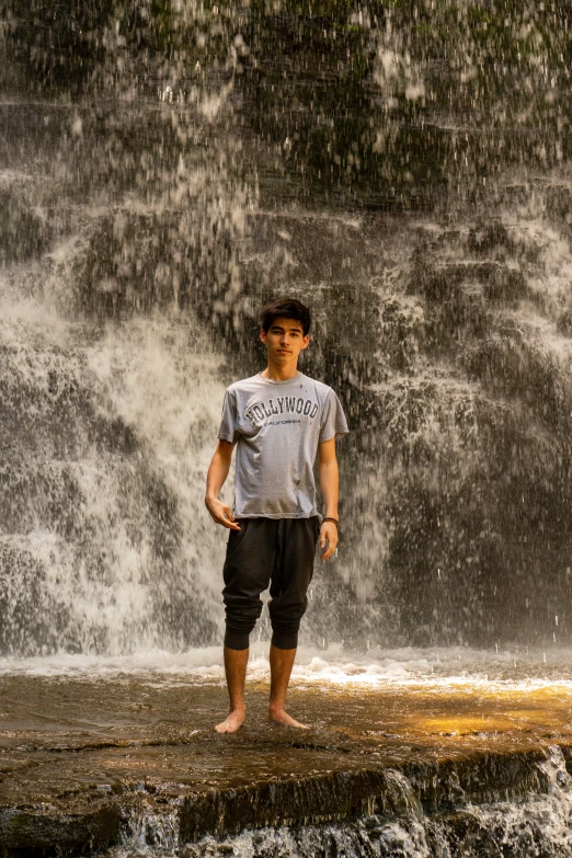 a boy standing in front of a water fall