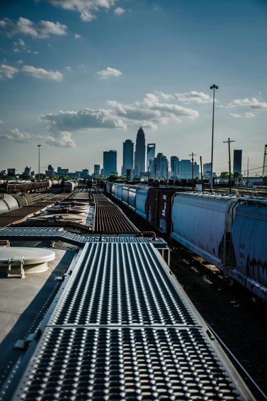 two trains passing by on train tracks with skyline in the background