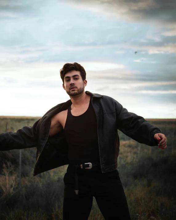 a man in black jacket with black shirt on posing