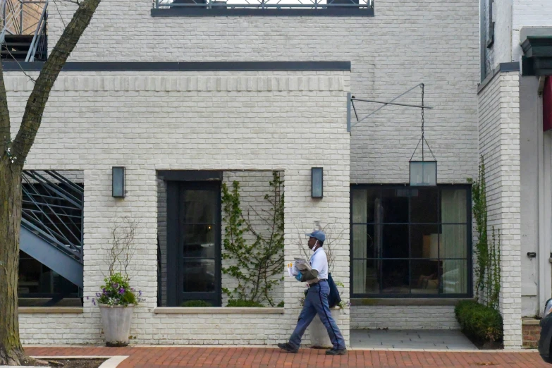 a man walking down a street past brick building