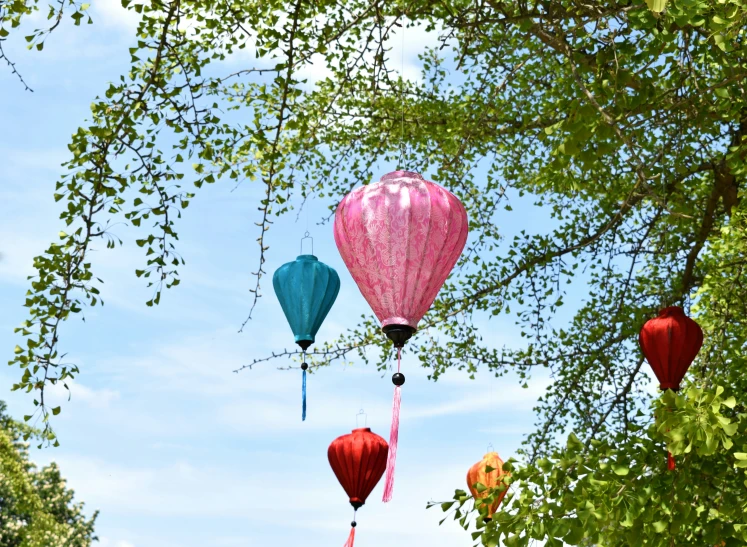 a number of different colored balloons flying in the sky