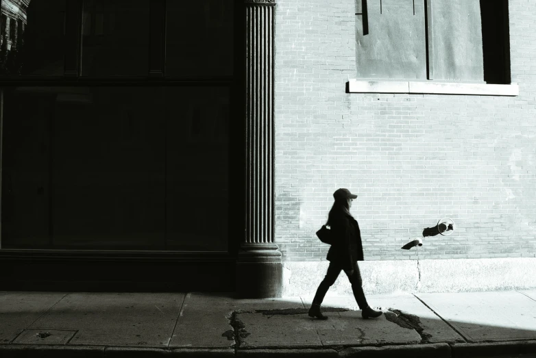a woman walking past a tall brick building