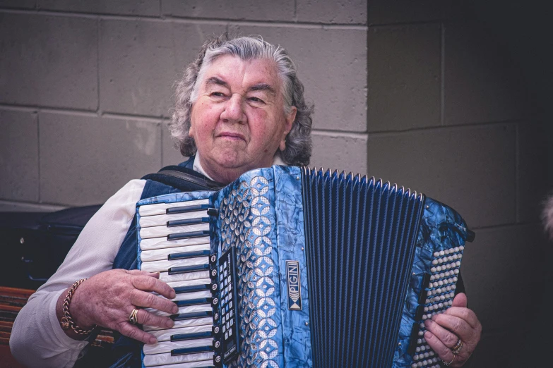 an older woman holding an accordion looking intently into the camera