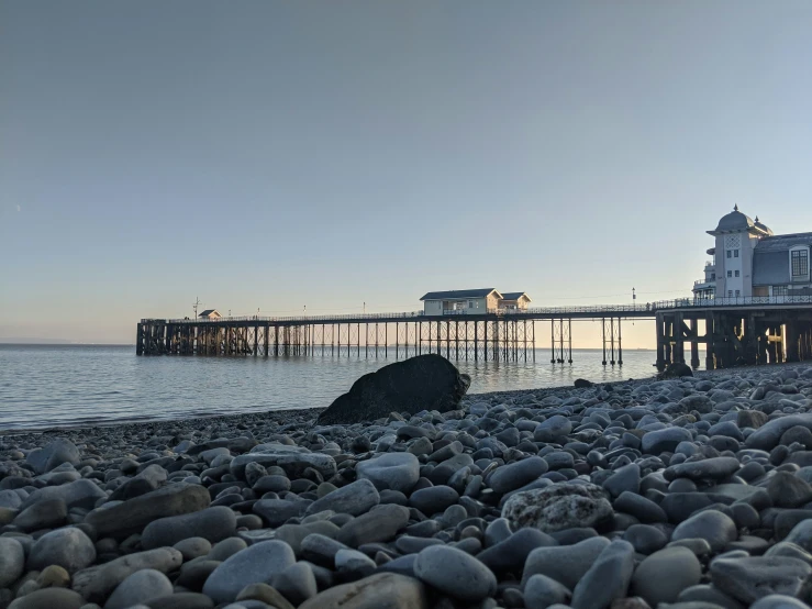 a long pier stands off the coast of a beach