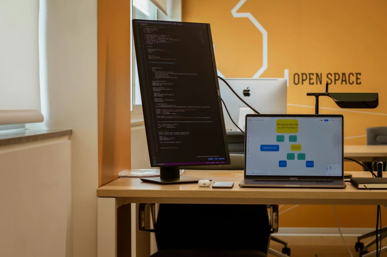 a desk with a laptop and desktop monitor