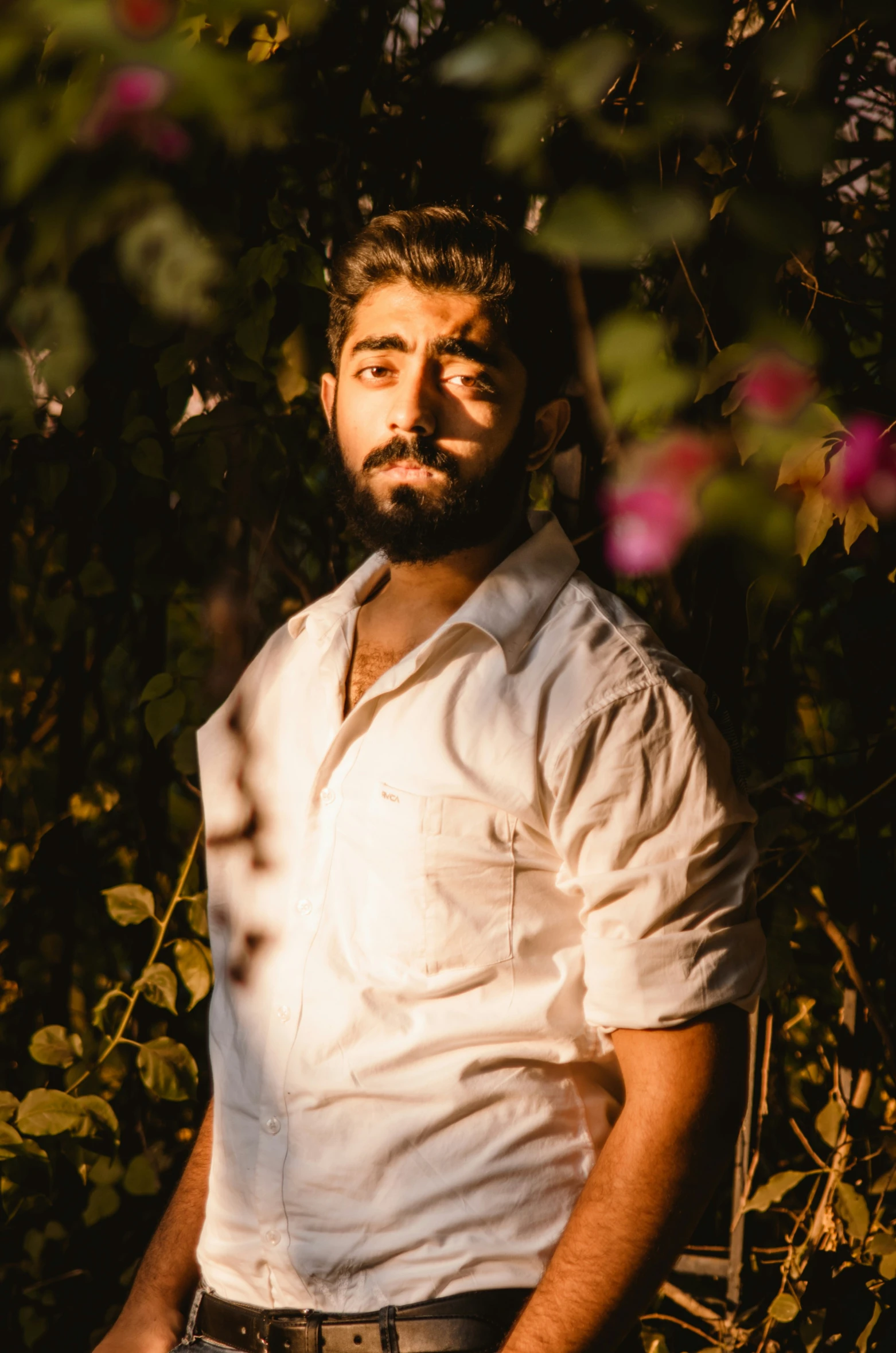 a man is standing by some flowers and posing