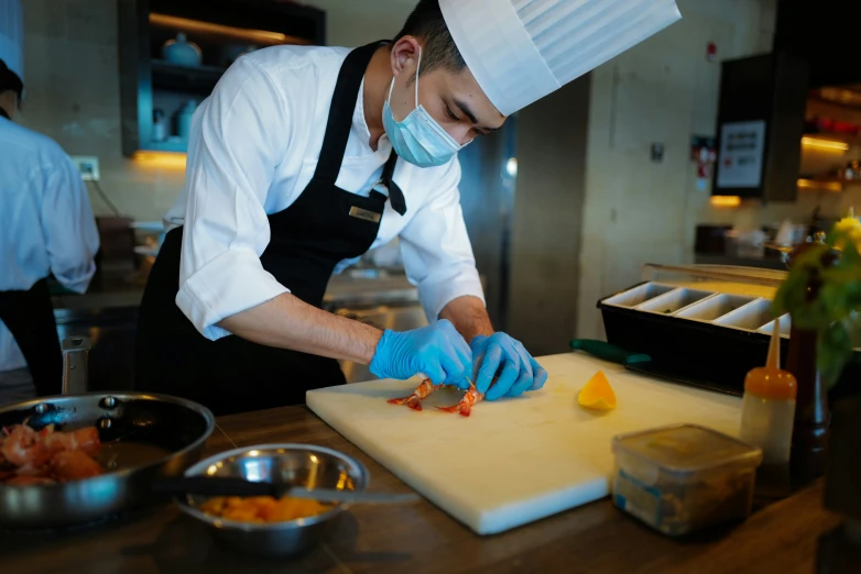 a chef wearing blue gloves is in the kitchen  vegetables