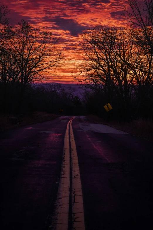 the sun is setting over a lonely road