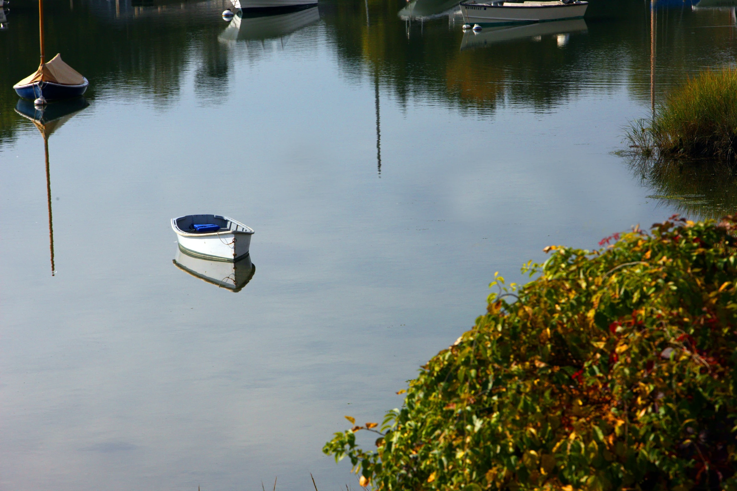 a small rowboat sitting on the water near moored boats