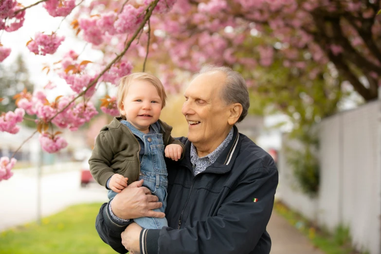 a man holds a toddler in his arms while they look into the distance