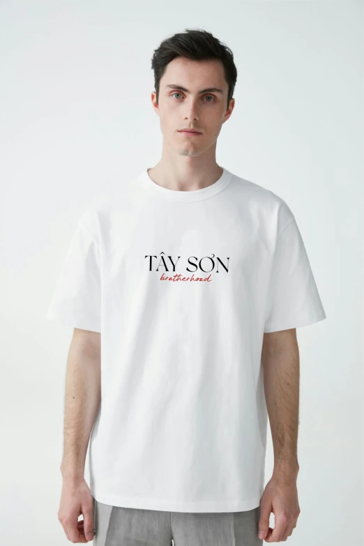 a man standing wearing a white ts - shirt that reads'fav son, a few years '