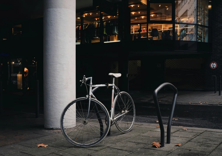 a bicycle  up to a silver rail outside a building