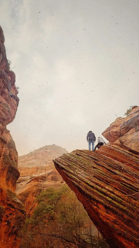 a person standing at the top of a steep rock formation