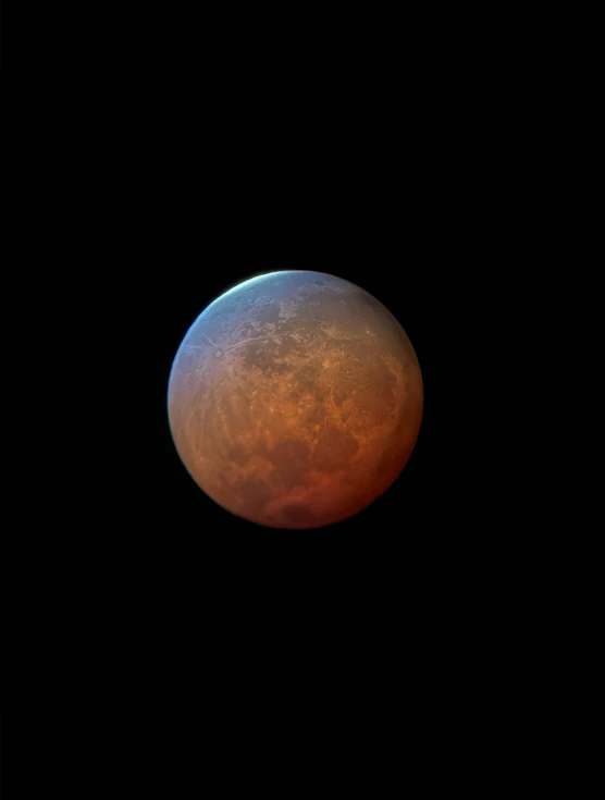 an orange moon seen from a distance with a black background