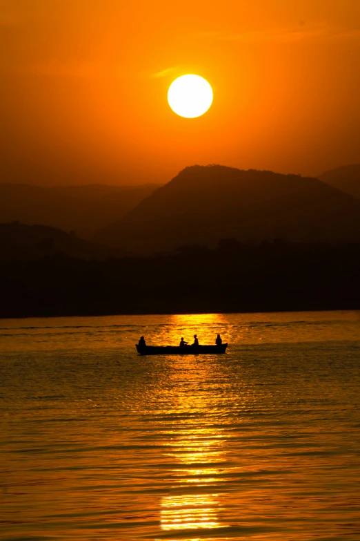 a boat floating in a large body of water at sunset