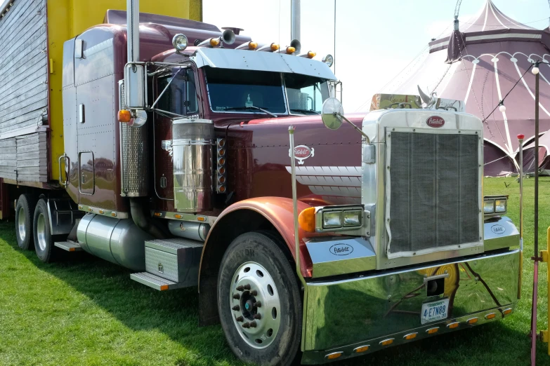 a large semi truck parked on top of a lush green field