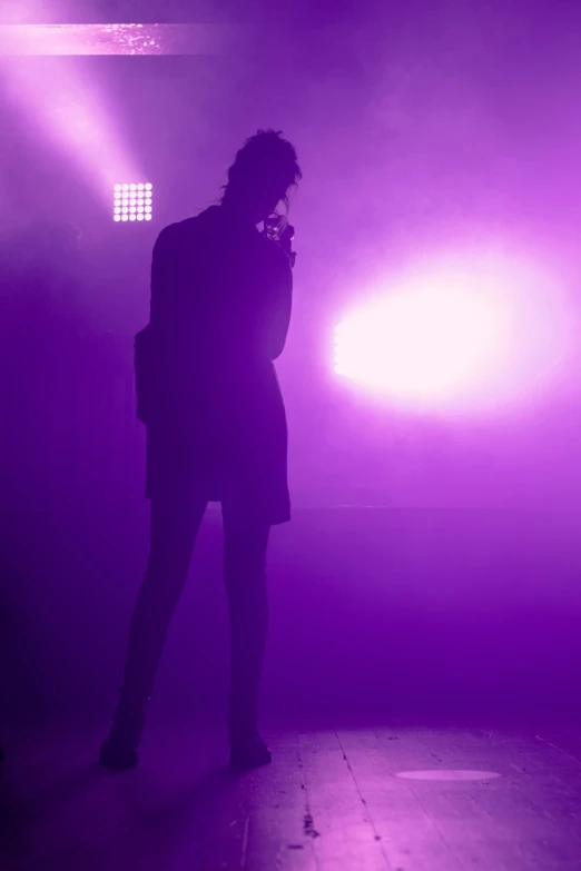 a woman is standing in a dark area with bright lights