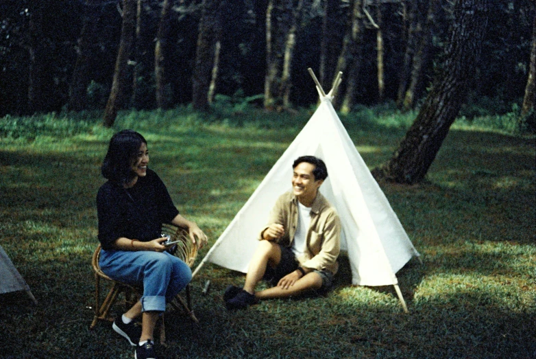 two people sitting next to a teepee