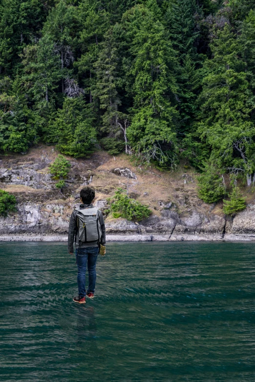 a man with a backpack stands in the water