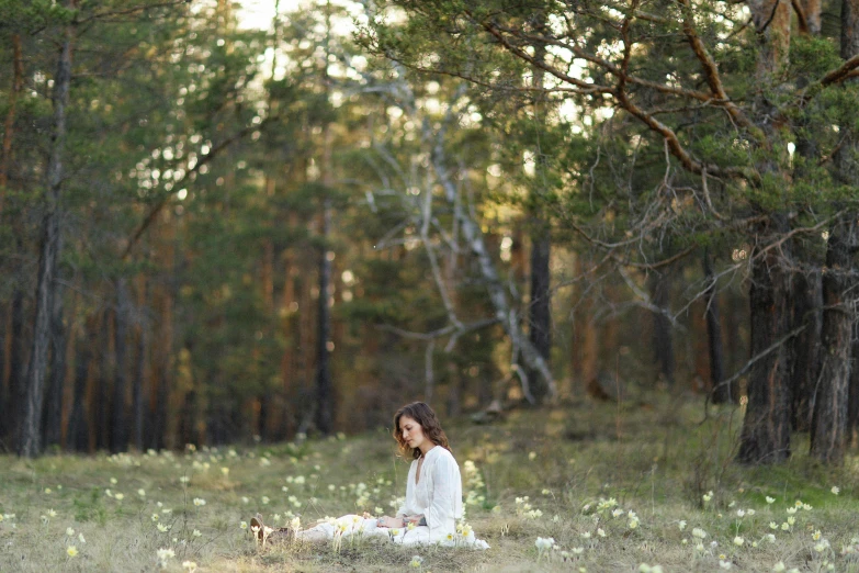a woman in white is sitting in a field