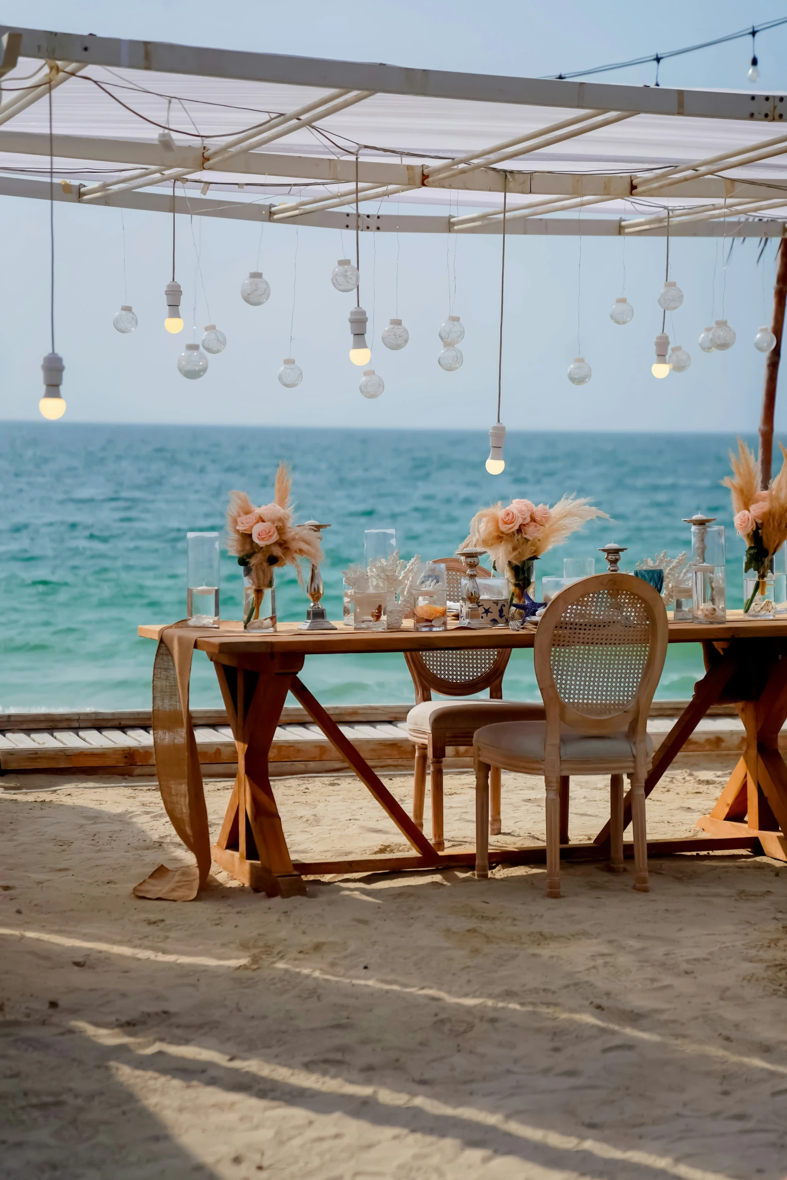 there is a dining table set for two on the beach