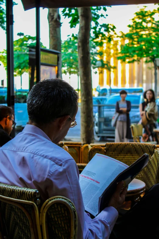 people sitting outside eating in chairs under trees