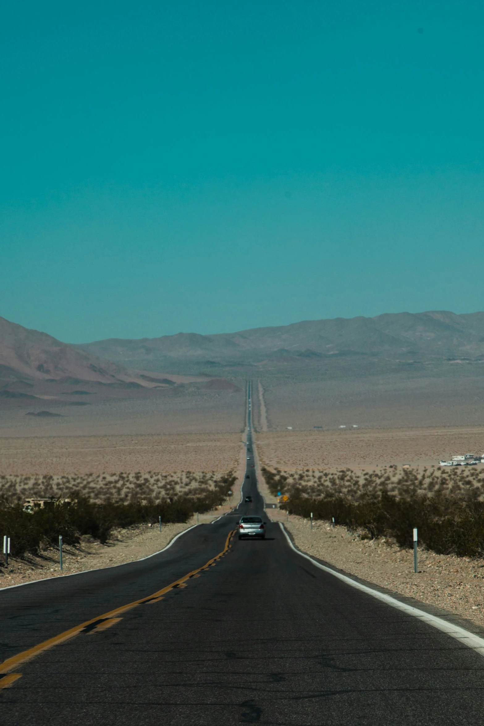long highway in desert with mountains in the background