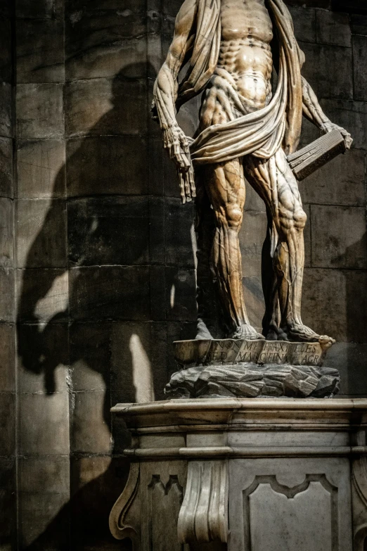 a statue is shown casting a shadow on a stone wall