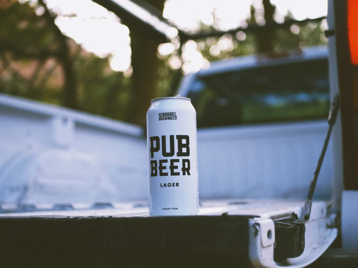 a can of pub beer sitting next to a white truck